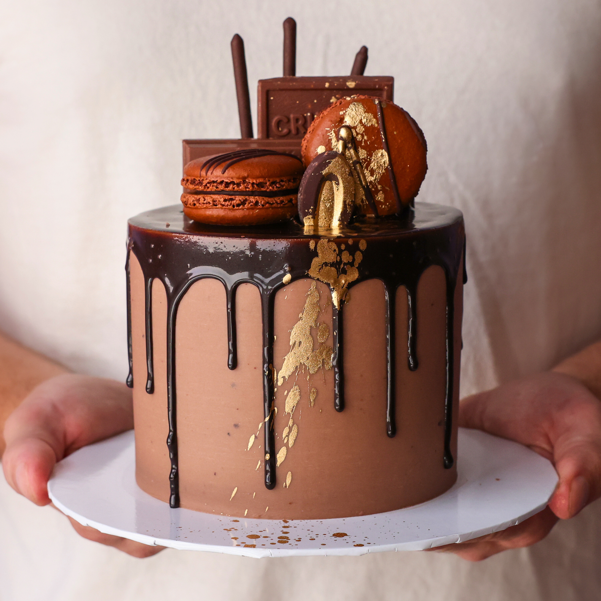 Chocolate cake with gold accents held by a person