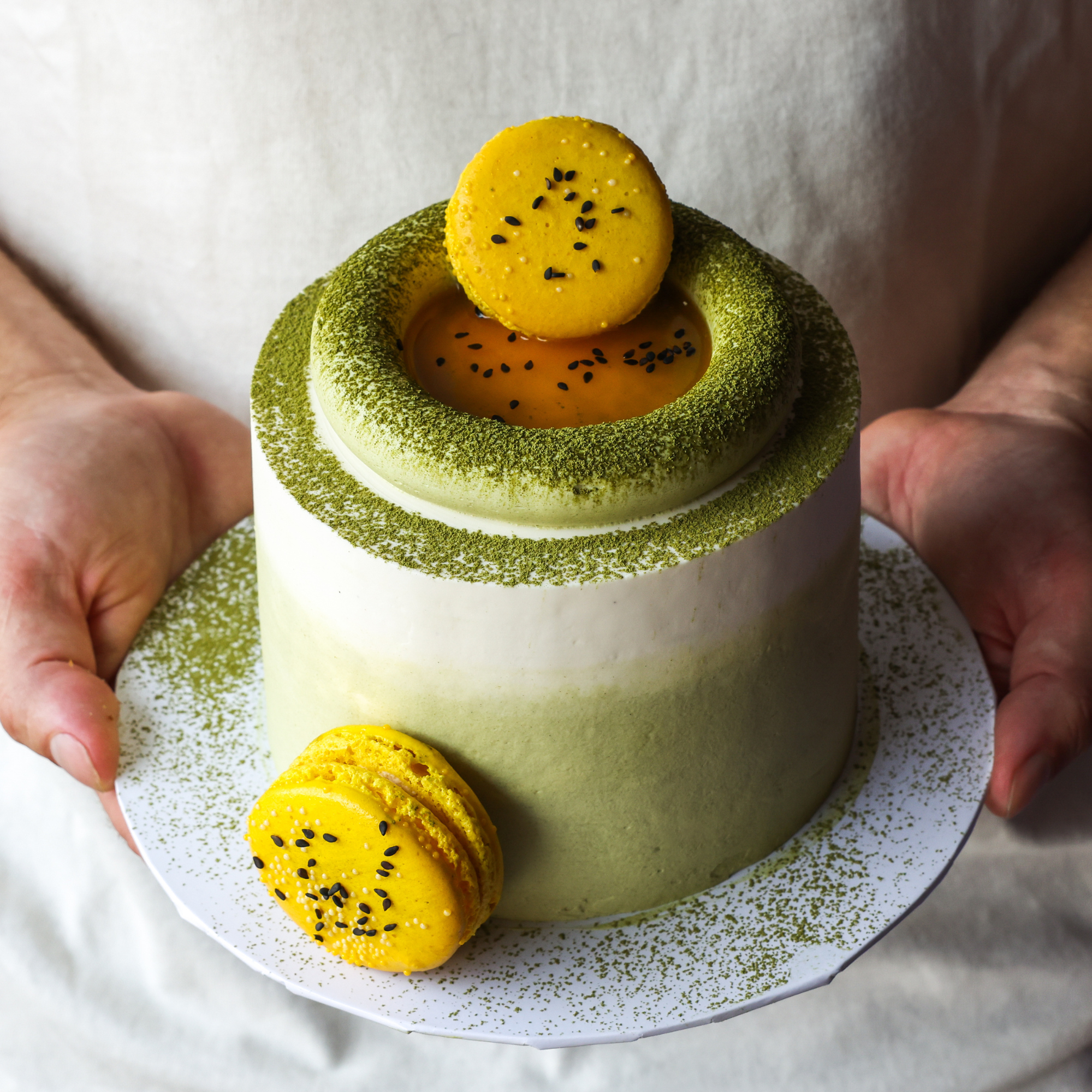 Green and white cake with yellow macarons on a white plate