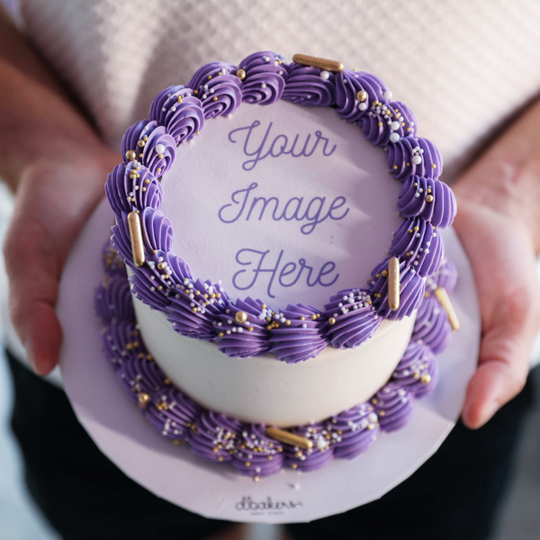 A custom photo cake with purple frosting and decorative elements, meant to resemble a graduation cap, with a placeholder text that reads 'Your Image Here'.