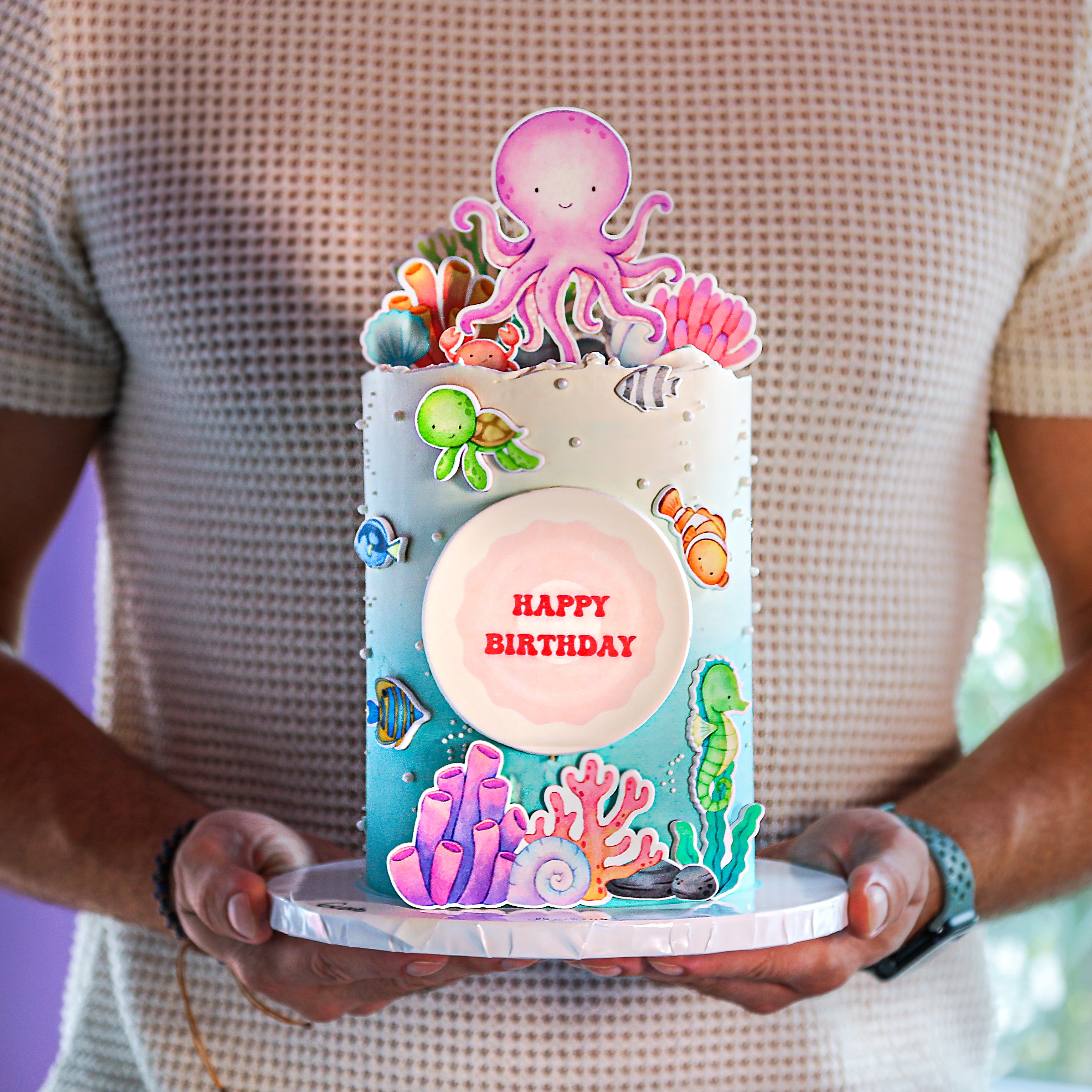 A decorated birthday cake with under the sea theme, including colorful aquatic animals and a 'Happy Birthday' message.